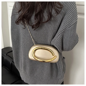 Champagne metallic hard shell bag featuring a bold horseshoe metal handle and chain strap