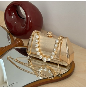 Detail der goldenen Abendclutch aus Metall mit Perlengriff und Schlangenkette