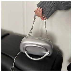 Detailed view of silver metallic hard shell evening bag with a round handle and chain strap