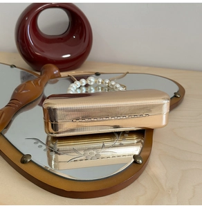 Detailaufnahme einer roségoldenen Abendtasche mit feinen Streifen und Scharnierverschluss