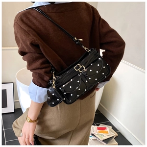 Détail d'un sac sous le bras à pois noirs avec deux poches et breloque en forme de cœur