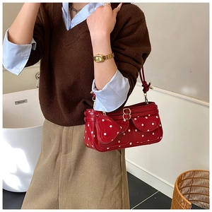 Détail du sac rouge à pois avec poches avant et pendentif en forme de petit cœur