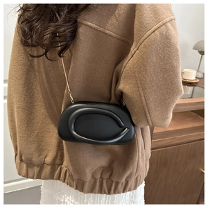 Detailed view of a black padded leather crossbody bag with a sleek gold chain strap on model