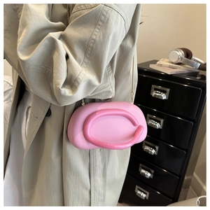 Pink jelly shoulder bag with 3D tubular trim shown on a model in a beige coat