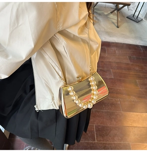 Detail der goldenen Abendtasche mit Perlengriff und Kette, getragen von einem Modell