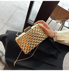 Detail einer goldenen unregelmäßigen Abendtasche mit Rautenmuster und Kette