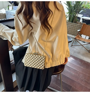 Detailansicht einer goldenen Abendtasche mit geometrischem Steppmuster und Goldkette