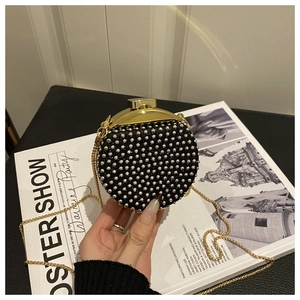Dettaglio di una mini borsa da sera rotonda con borchie e tracolla a catena dorata