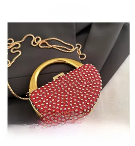 Macro detail of red semi-circular evening bag with rhinestones and gold ring handle