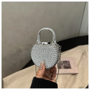Close-up of a heart-shaped silver evening bag with rhinestones and metal handle