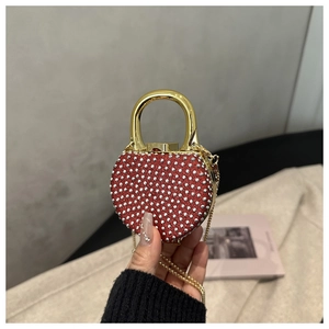 Detailed view of red heart-shaped evening bag with sparkling silver rhinestones and gold handle