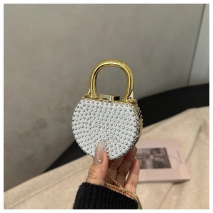Detail view of the round rhinestone dinner clutch with a large gold metal handle