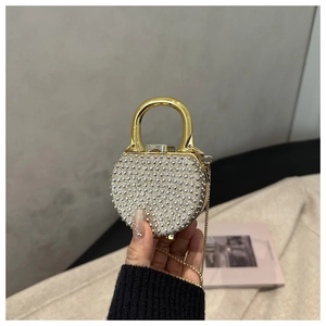 Close-up of heart-shaped rhinestone evening clutch with gold metal U-handle and chain