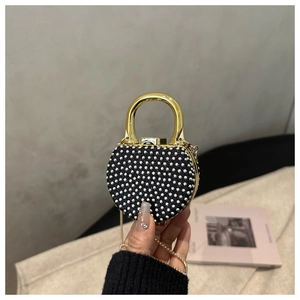 Close-up of heart-shaped evening bag with silver rhinestones and gold metal handle