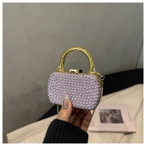 Close-up of pink mini acrylic evening bag with sparkling rhinestones and gold handle