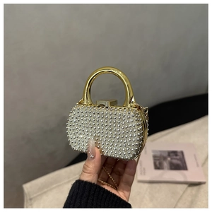 Close-up of rhinestone evening bag with gold circular handle and crossbody chain strap