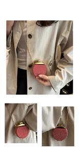 Dettaglio di una mini borsa da sera tonda rossa con perle bianche e catena dorata