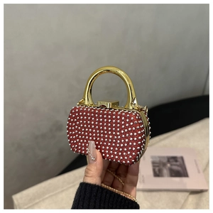 Close-up of mini red evening clutch with silver rhinestones and gold arc handle