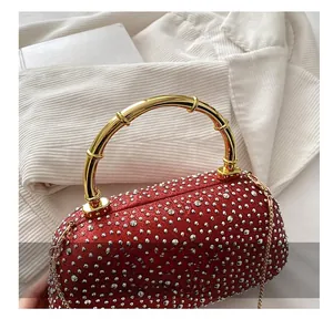 Close-up of red rhinestone evening bag with gold bamboo handle and metallic chain strap