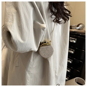Dettaglio della mini borsa rotonda con perle bianche e catena dorata sulla modella