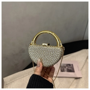 Detail of elegant heart-shaped evening bag with white rhinestones and gold handle
