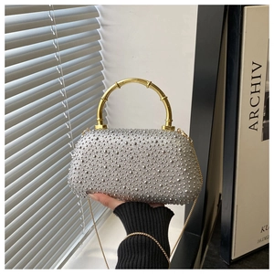 Close-up of silver rhinestone evening bag featuring a vintage gold bamboo metal handle