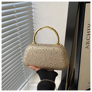 Close-up of champagne gold rhinestone evening bag with elegant bamboo top handle