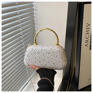 Detail of the white silk clutch with silver rhinestones and gold bamboo handle