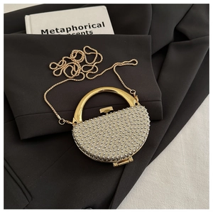 Close-up of semi-circle evening clutch with sparkling beads and gold metal handle
