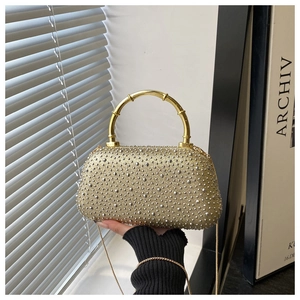 Detail of evening clutch bag featuring rhinestone finish and golden bamboo top handle
