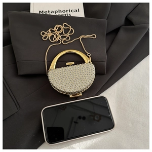 Detail of semicircular evening bag with silver rivets and golden ring handle