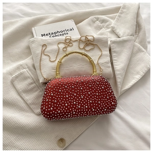 Detailed shot of a red rhinestone evening bag featuring a gold bamboo-shaped handle