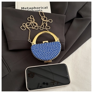 Detail of royal blue rhinestone evening bag with gold metal handle and chain strap