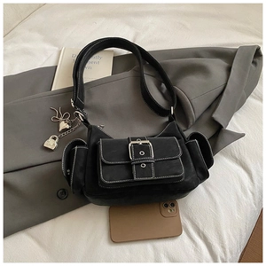 Detail of black suede utility crossbody bag with metal buckles and heart charm pendant