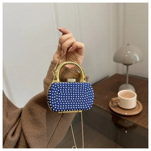 Blue mini evening bag with silver studs and golden metal handle in a lifestyle setting