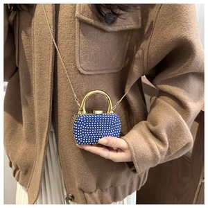 Detail of royal blue rhinestone mini box bag with gold handle and chain strap on model