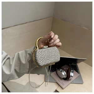 Detailed view of silver rhinestone evening bag with gold handle and chain strap