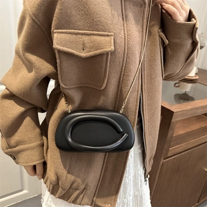 Minimalist black oval clutch bag with golden chain strap and unique ring design