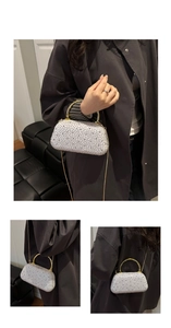 Detail of silver rhinestone evening clutch bag with golden bamboo handle and chain strap