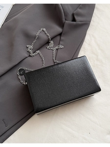 Detail of black rectangular evening clutch with cross-pattern texture and silver chain strap