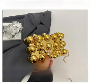 Detail einer goldenen Clutch mit Kugelstruktur, Metallblasen und Kettenriemen