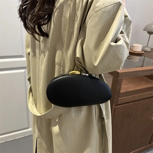 Elegant black oval hard shell clutch with gold and silver orb clasp on metal chain