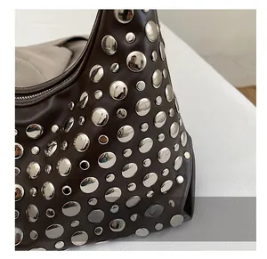 Close-up of silver metal rivets on dark brown leather handbag with zipper detail