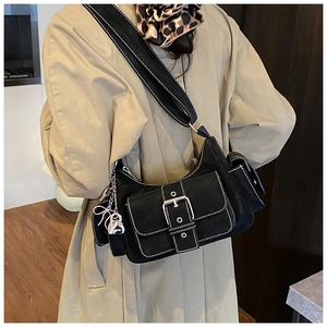 Detail of black suede crossbody bag with white stitching and silver heart lock charm