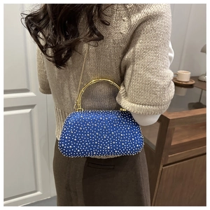 Dettaglio della borsa da sera con strass blu con manico in bambù dorato e tracolla sulla spalla