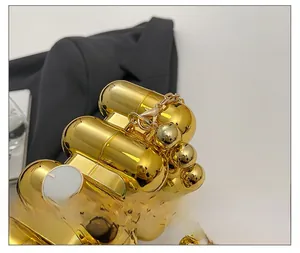 Makroaufnahme der polierten goldfarbenen Acryl-Clutch mit glatter metallischer Kugelkette