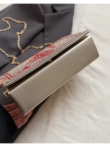 Close-up of champagne evening bag with rhinestones, red lip motif and gold chain