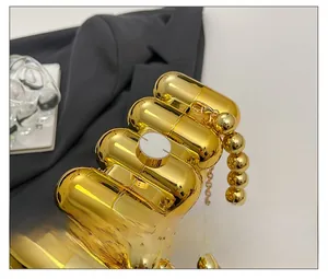 Detailaufnahme der goldenen Kapsel-Abendtasche mit Hochglanz-Finish und Schnappverschluss