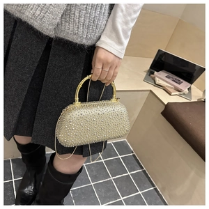 Dettaglio borsa da sera dorata glitterata con manico in bambù e catena in metallo