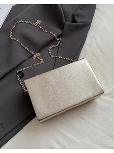 Macro view of champagne gold evening clutch featuring refined cross-grain texture and chain